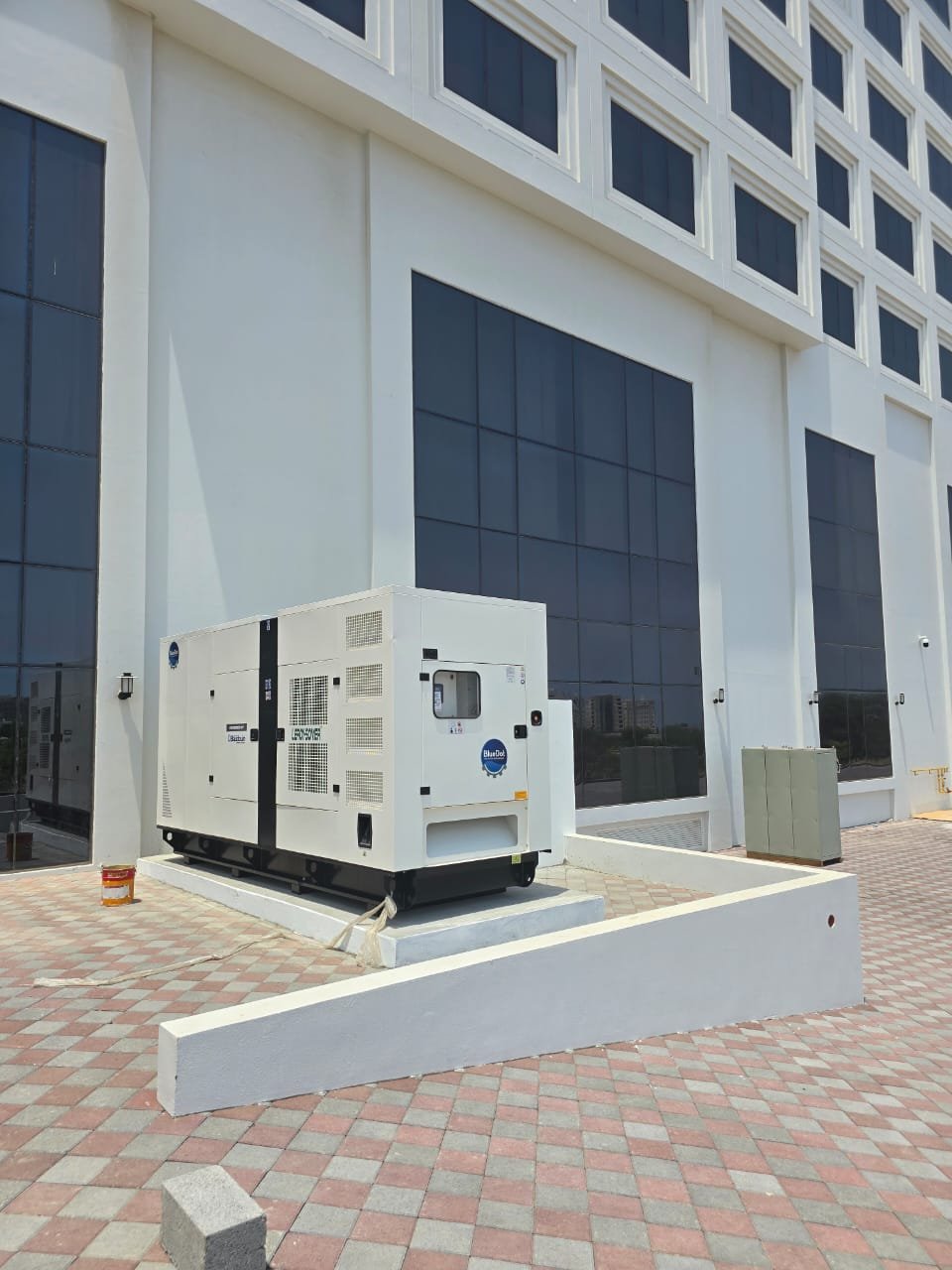 WhatsApp Image 2024-08-13 at 12.09.39 PM (1) A white diesel generator in open area.